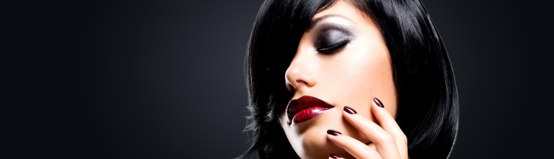 Frau mit dunklem Bob, betonten Augen, rotem Lippenstift und dunkel lackierten Nägeln